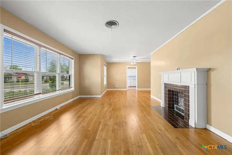 Main living room with hardwood floors, wide windows and fireplace