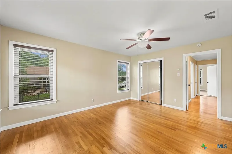 Primary bedroom with hardwood floors and mirrored closet doors